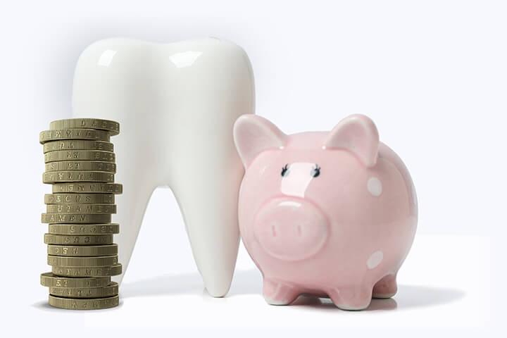 Stack of £1 coins, model of tooth and piggy bank